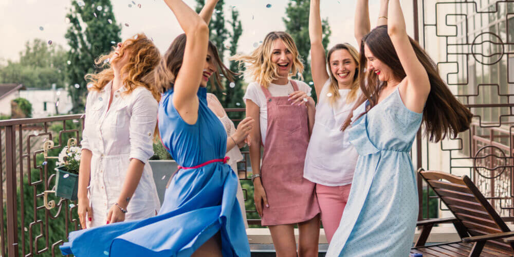 women on a hen party dancing on a terrace with confetti in the air 